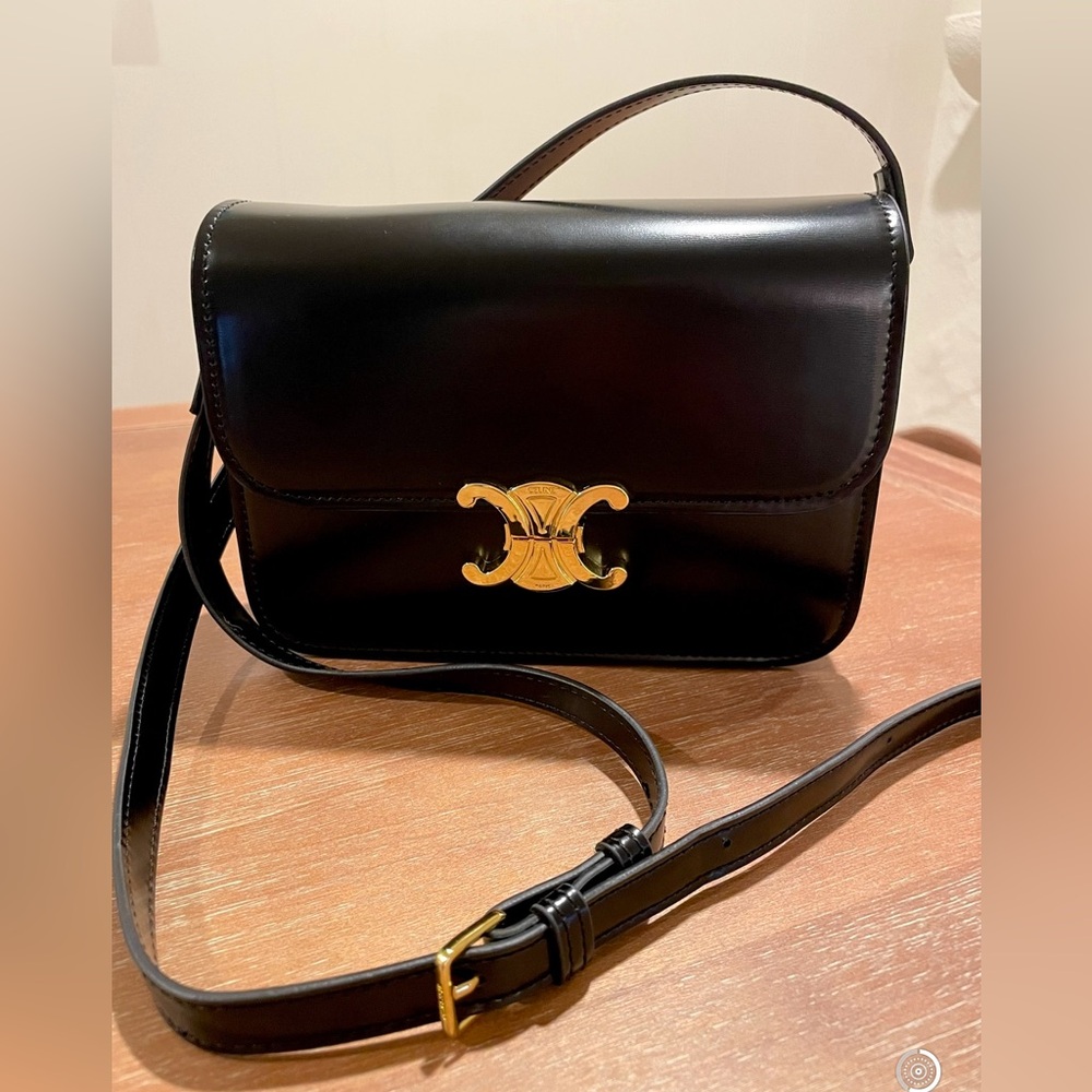 Black leather bag with gold emblem and adjustable strap
